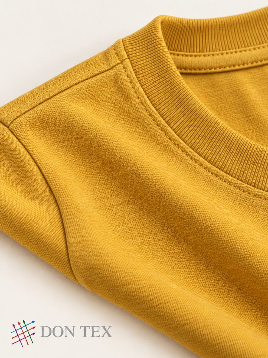 Close-up of the rib neckband and shoulder seam on mustard jersey