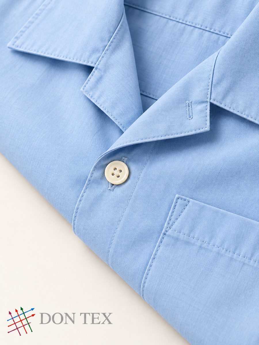 Close-up of a camp collar and button on woven cotton-type cloth